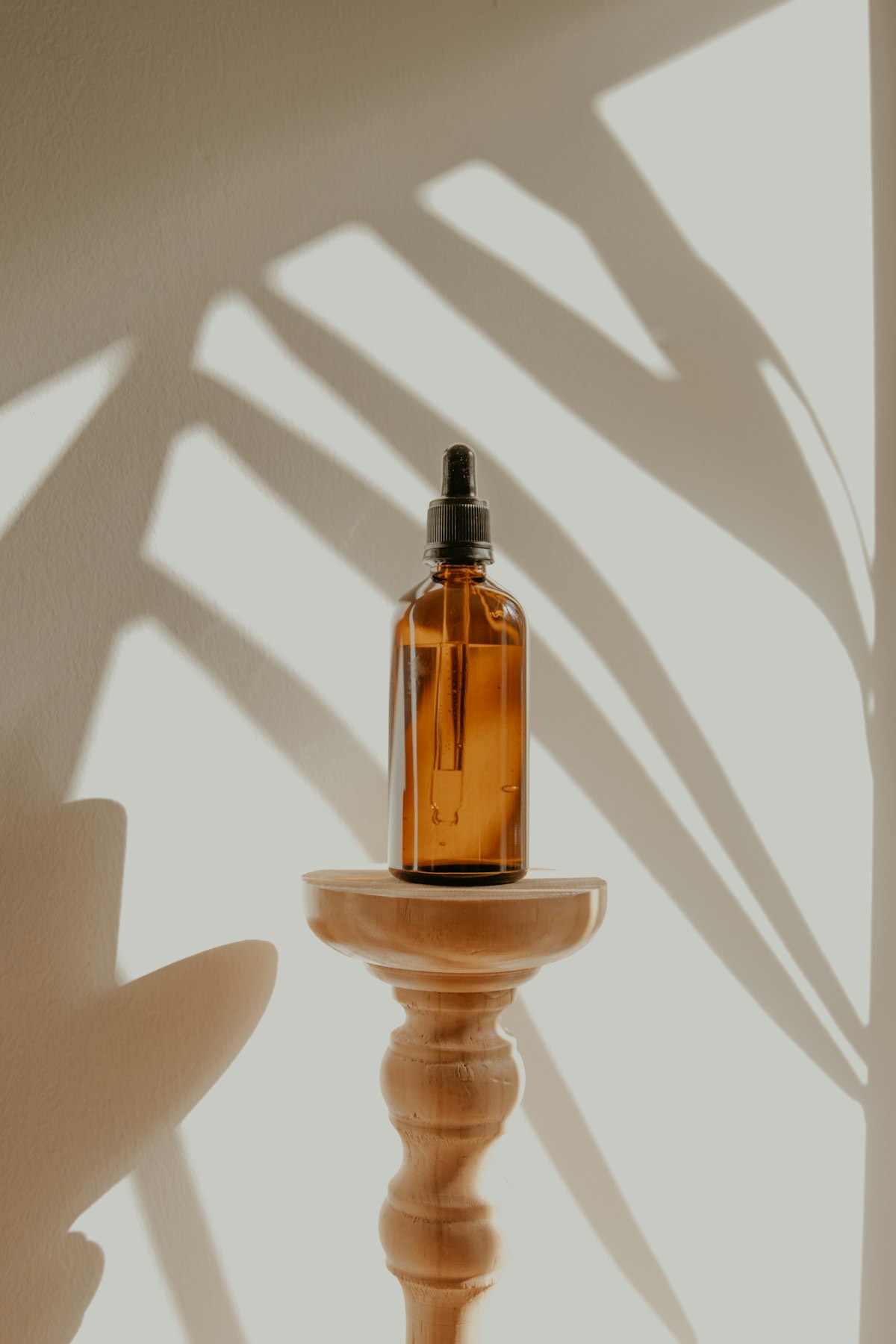 An amber serum bottle casting long shadows